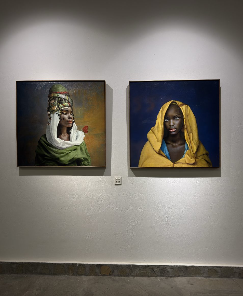 Woman with a tall turban and red butterfly, beside a woman in a yellow hood